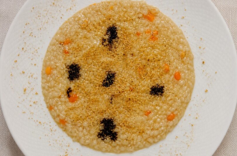 Risotto Acquerello con crema di cipolla paglierina Risotto Acquerello con crema di cipolla paglierina, riduzione di Merlot, zeste d’arancia e granella di pistacchio